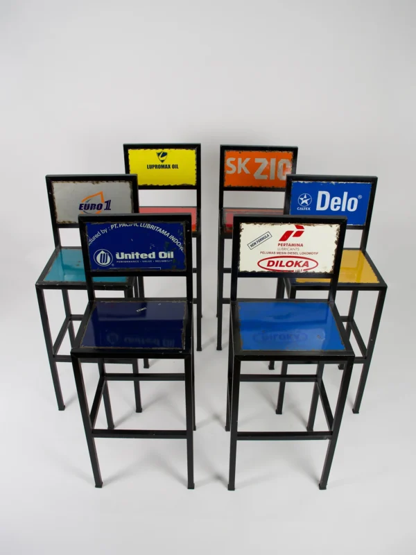 Handgemaakte barkrukken van gerecycled metaal met zwarte frames en kleurrijke zittingen en rugleuningen met originele prints.