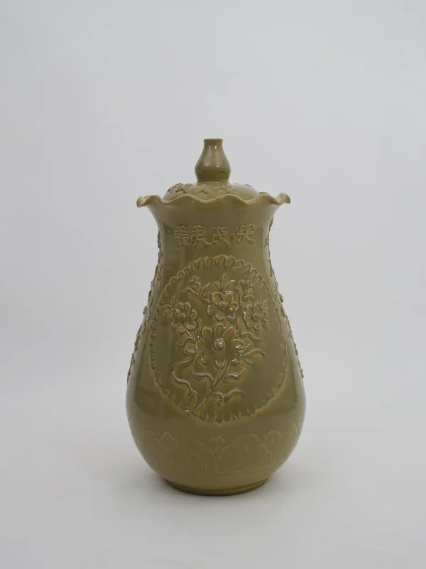Dorothy Vase – olijfgroene keramieken vaas met deksel, bloemreliëf en sierlijke golvende rand.