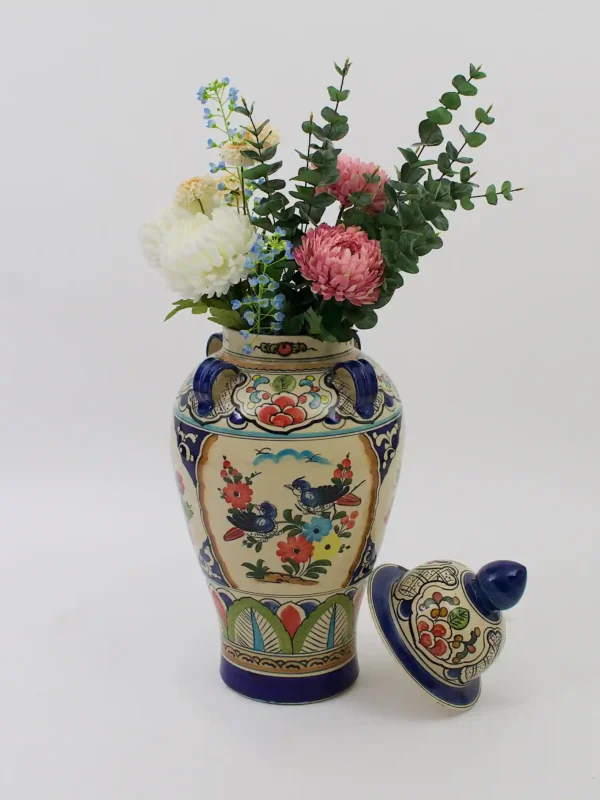 Alt-tekst: Frida Vase – kleurrijke keramieken vaas met deksel, handgeschilderde bloemen, vogels en decoratieve handgrepen.